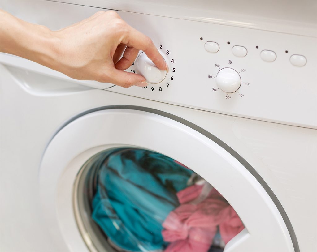 mano de mujer colocando el programa de la lavadora ahorro de energía
