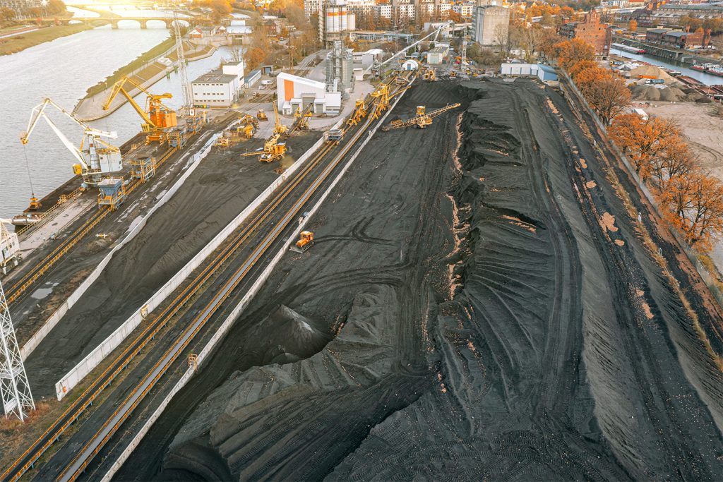 grandes pilas de carbon y vista de arriba de un almacén de carbón descargando y cargando carbon con excavadoras y transportistas llevándolo en una fotografía aérea