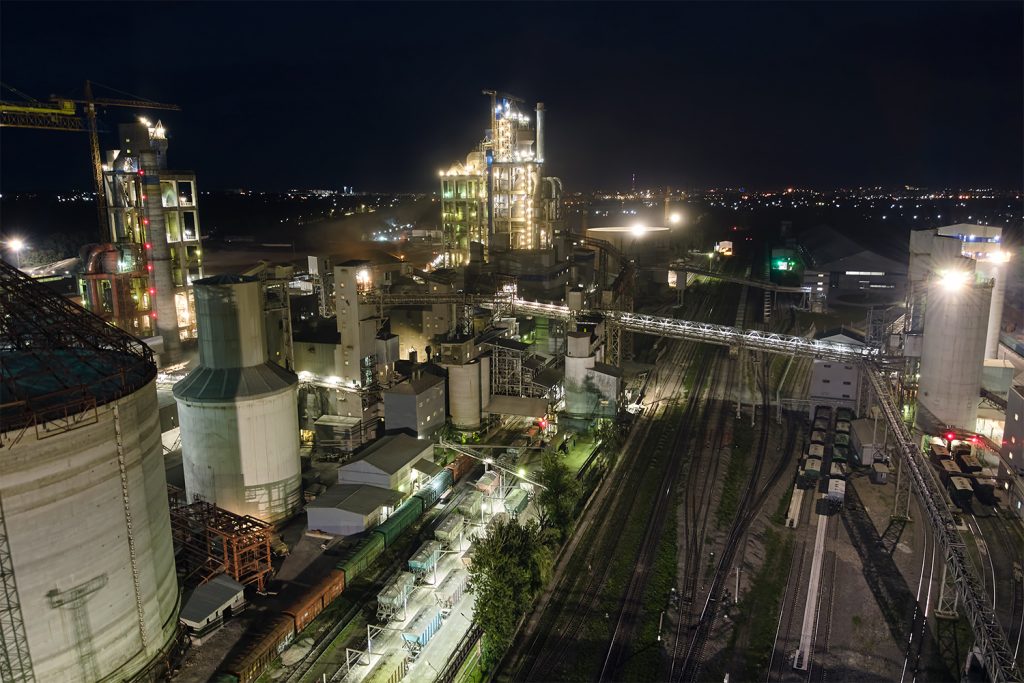 vista area de empresa de cemento con estructura de gran planta de concreto y torres de produccion en un area industrial en la noche manufactura e industria global