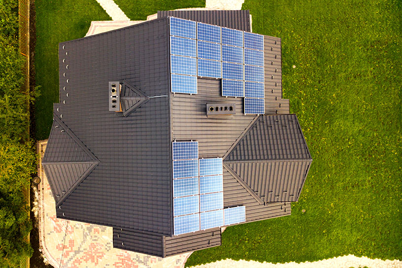Vista aérea de una casa privada rural con paneles solares fotovoltaicos para producir electricidad limpia en el techo. Concepto de hogar autónomo.
